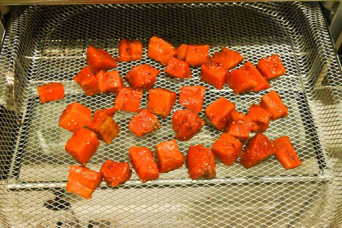 teriyaki salmon cubes in an air fryer tray.