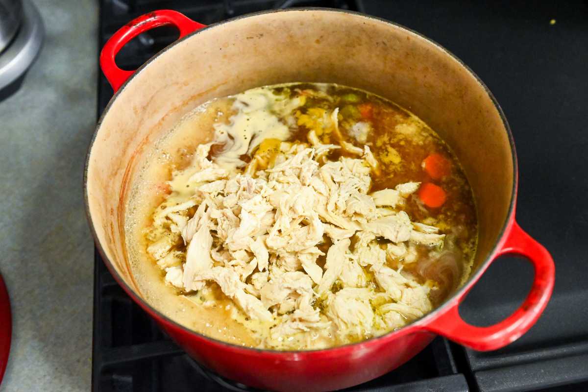 cooked chicken in broth in a red pot.