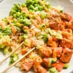 close up of a teriyaki salmon bowl with chopsticks.