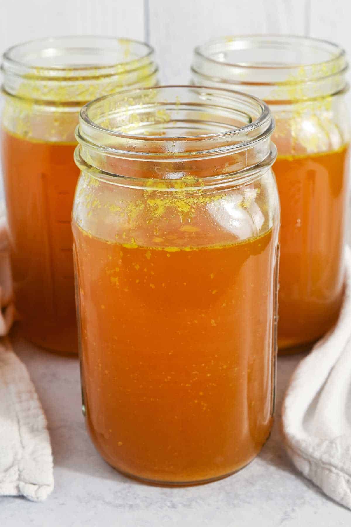 three jars of homemade bone broth in a pyramid shape.