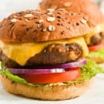 close up of pub burger made with worcestershire sauce on a seeded bun with american cheese, lettuce, tomato, and red onion.