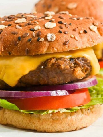 close up of pub burger made with worcestershire sauce on a seeded bun with american cheese, lettuce, tomato, and red onion.