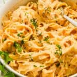close up of cajun pasta fettuccine topped with parsley.