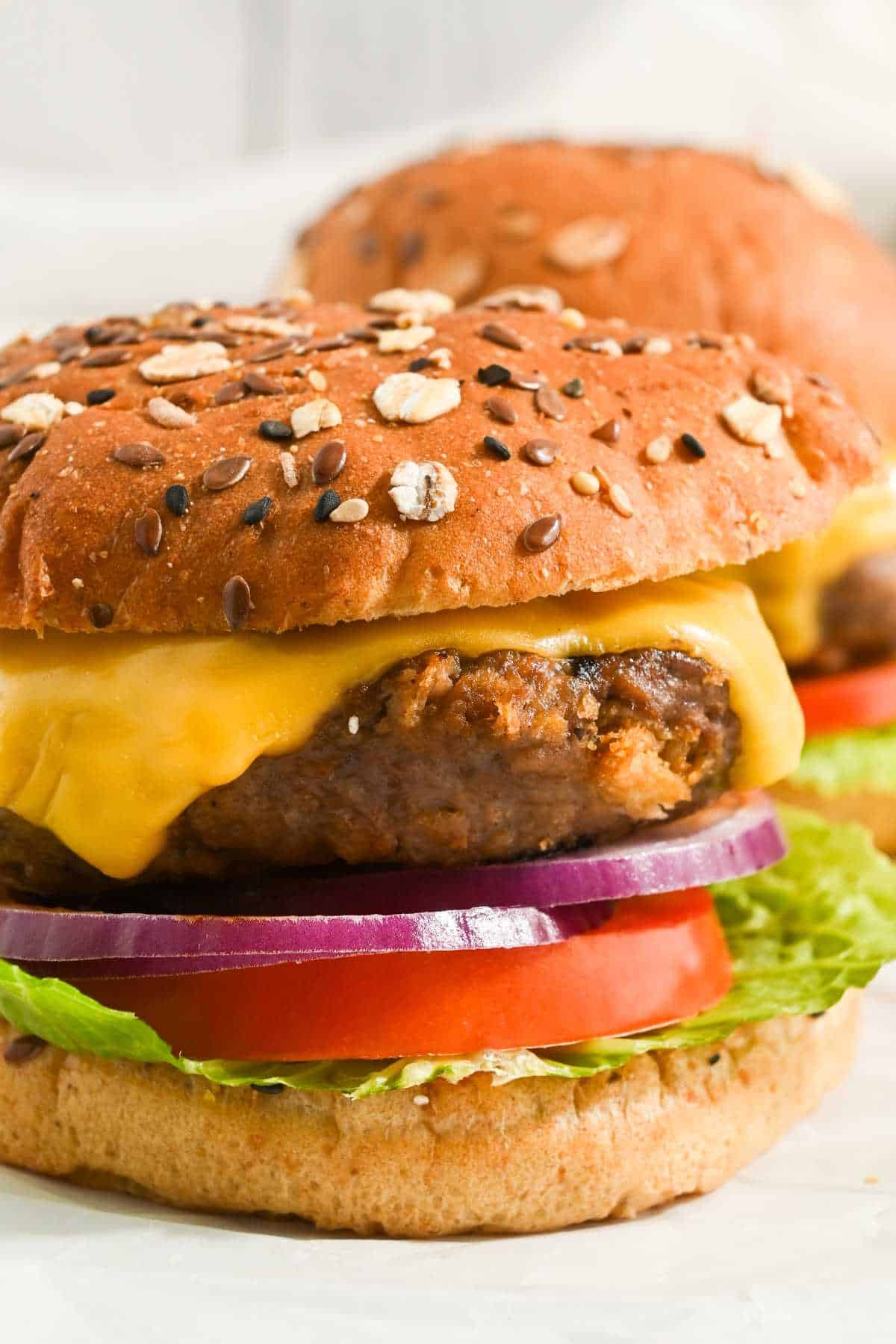 view of two pub burgers made with worcestershire sauce on a seeded bun with american cheese, lettuce, tomato, and red onion.