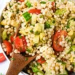 close up of avocado couscous salad with a wooden spoon.