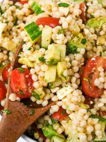 close up of avocado couscous salad with a wooden spoon.