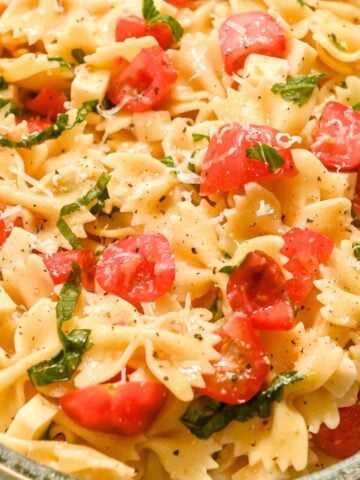 square featured photo of bow tie caprese pasta salad with parmesan, cherry tomatoes, and basil.