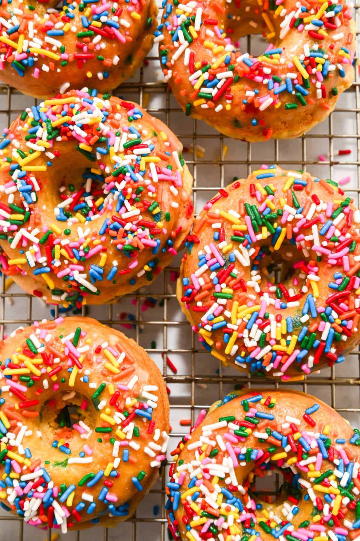 six funfetti donuts on a cooling rack.
