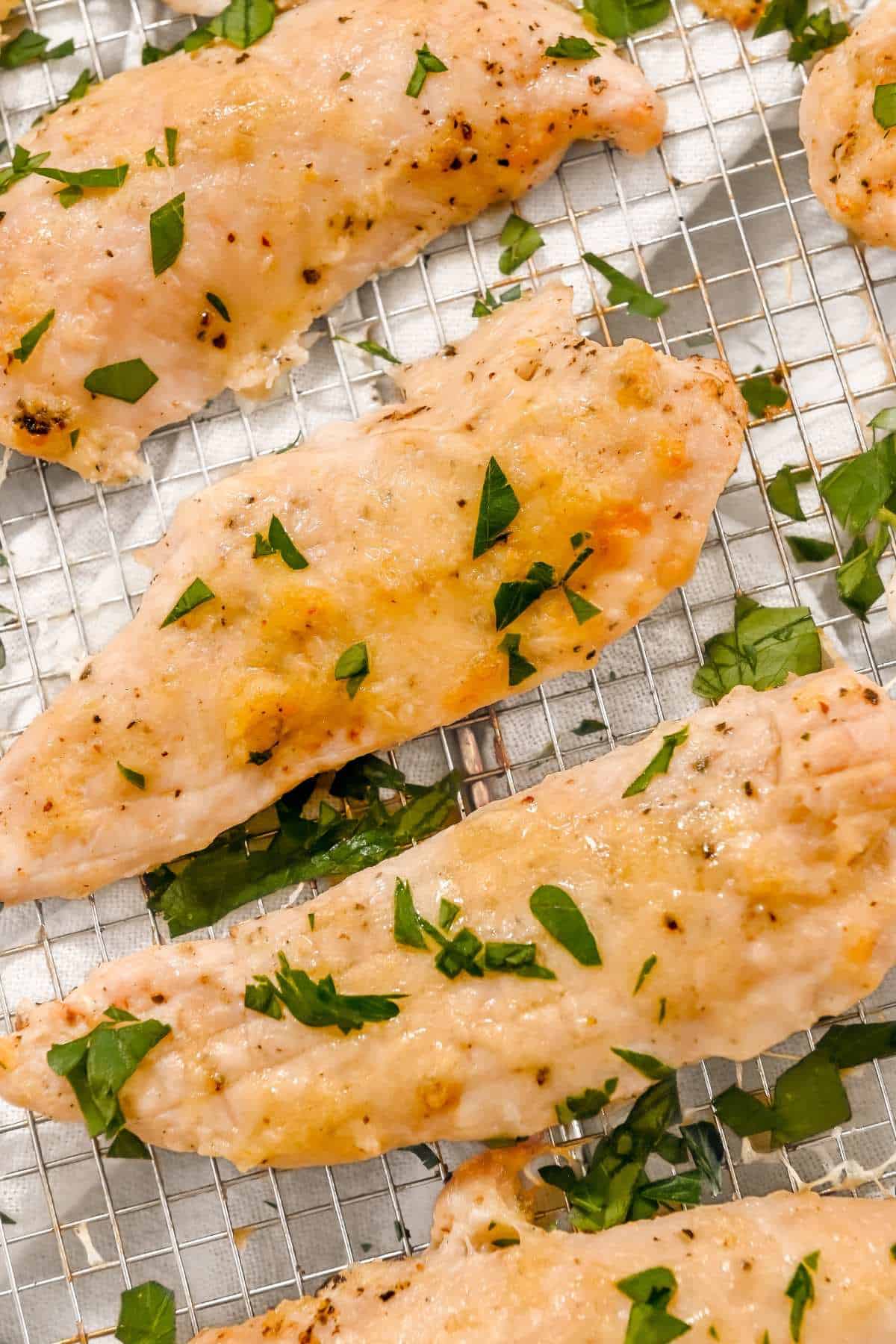close up of garlic parmesan chicken tenders topped with parsley.