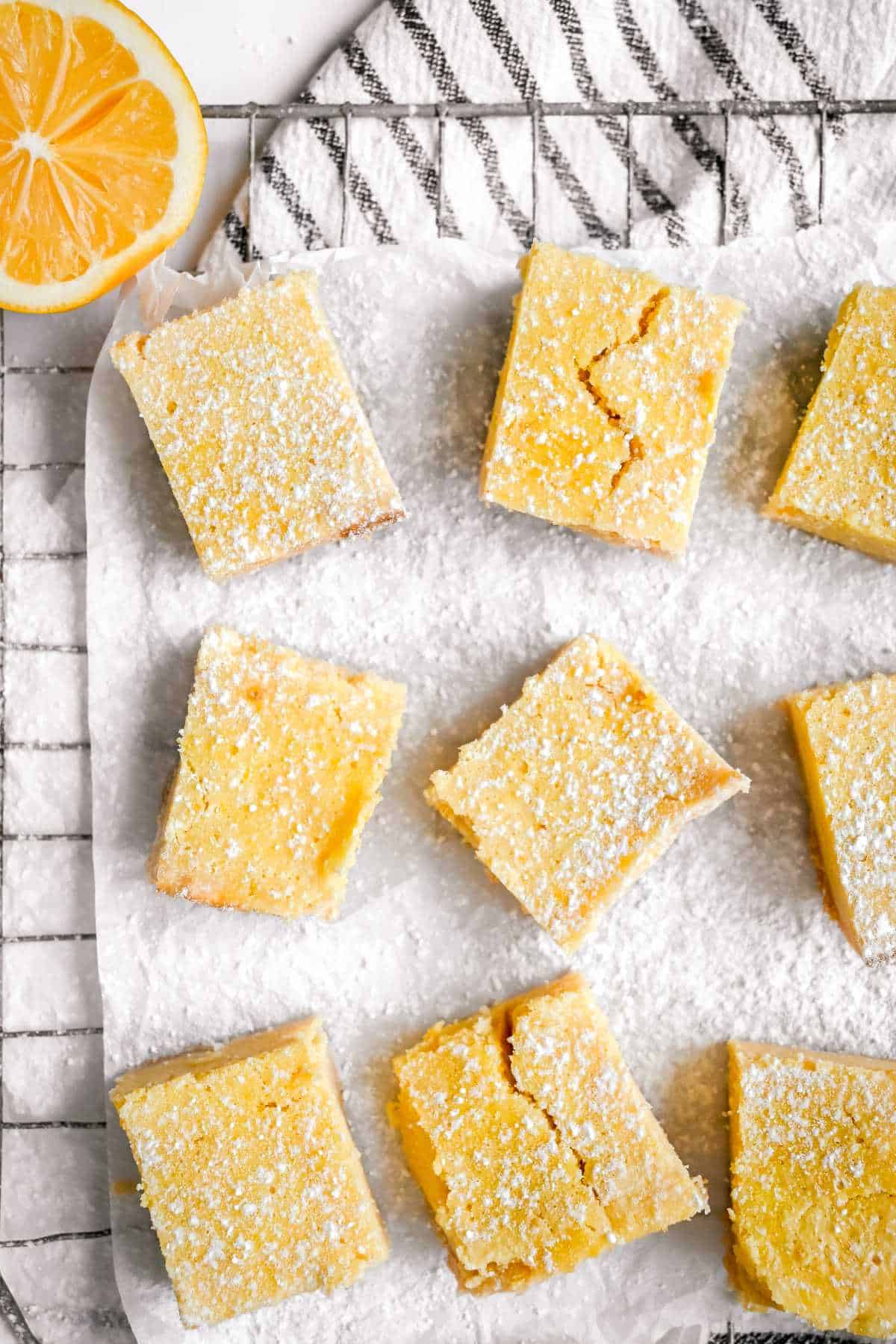 cut meyer lemon bars on parchment paper on a cooling rack.
