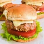close up shot of turkey burger sliders on Hawaiian rolls with cheese, lettuce, and tomato.