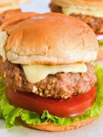 close up shot of turkey burger sliders on Hawaiian rolls with cheese, lettuce, and tomato.