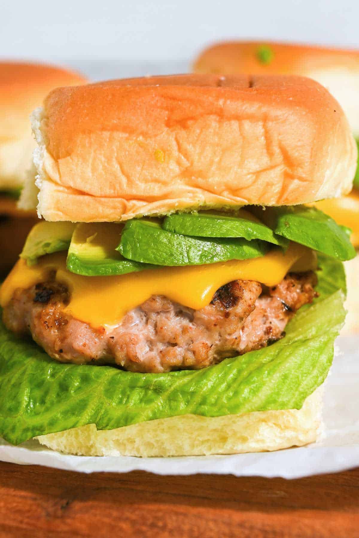 turkey burger slider with cheese, avocado, and lettuce on a Hawaiian roll.