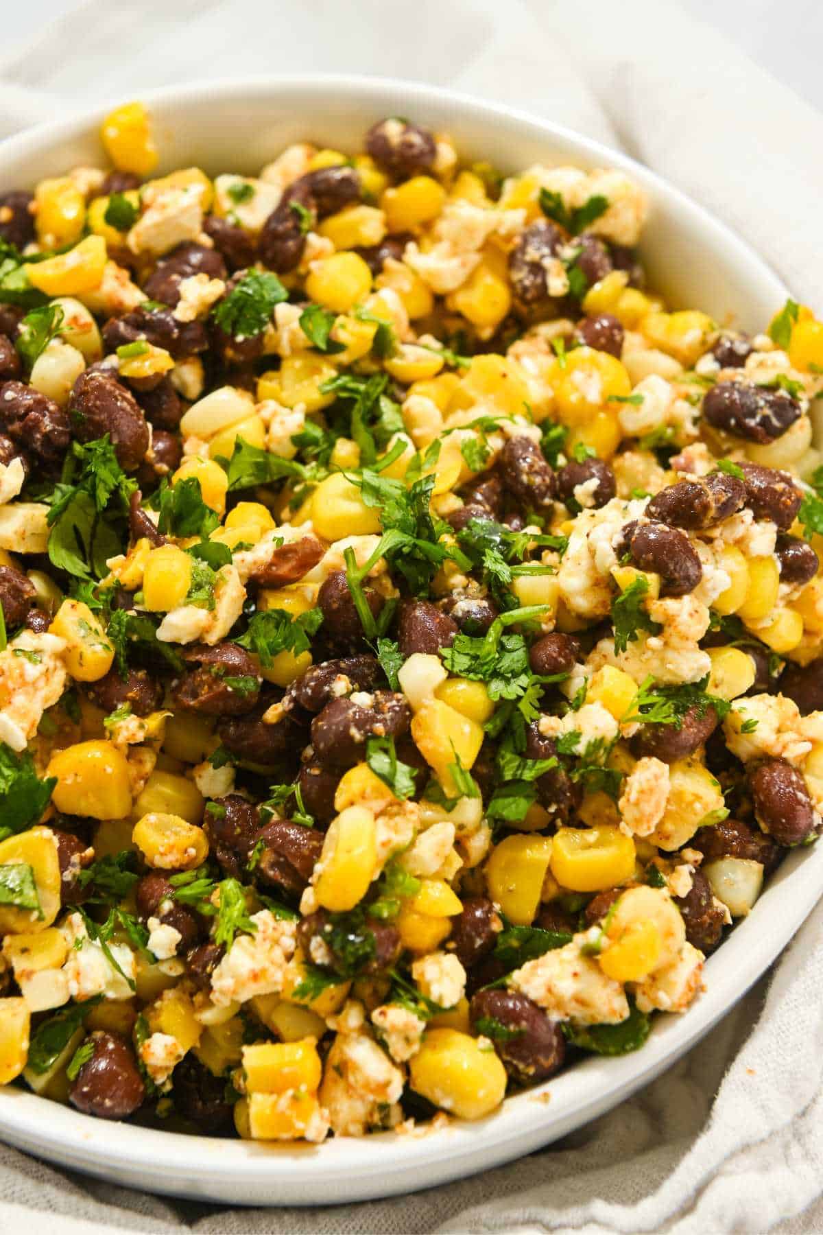 corn, black bean, and feta dip in a white bowl topped with cilantro.