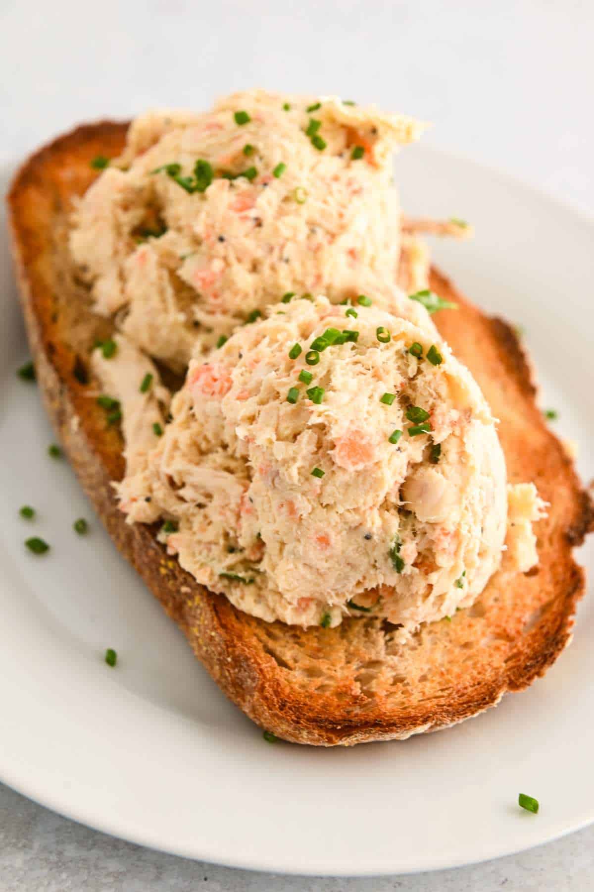 two scoops of cottage cheese chicken salad on bread toast on a white plate.