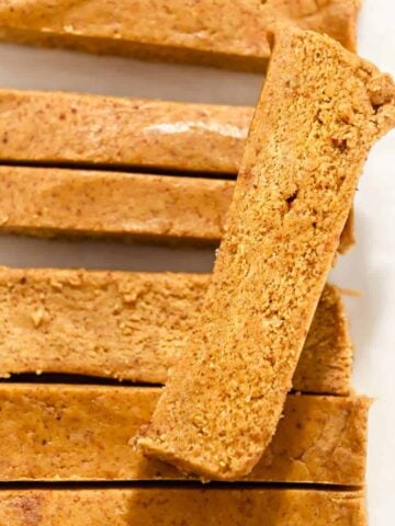 close up shot of a pumpkin protein bar on top of other pumpkin protein bars.