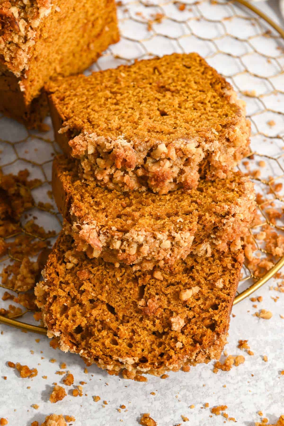 three slices of pumpkin walnut bread laying on a wire rack.