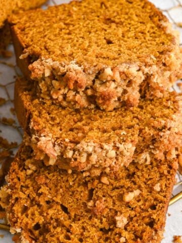 close up of three slices of pumpkin walnut bread laying on a wire rack.
