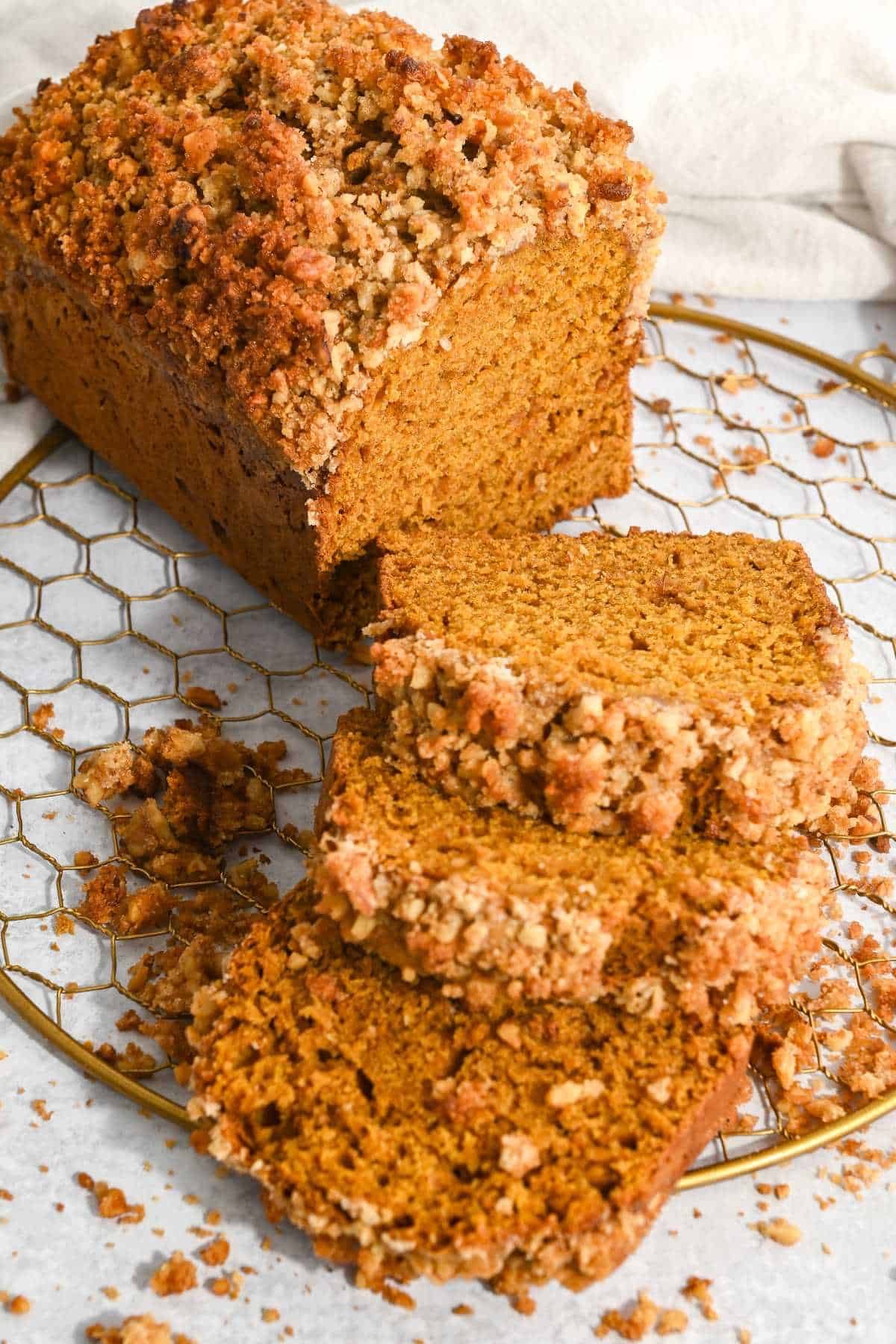 view of pumpkin walnut bread cut into three slices laying down with the rest of the loaf behind it.
