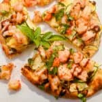 close up shot of a slice of shrimp pizza topped with fresh basil and balsamic glaze.