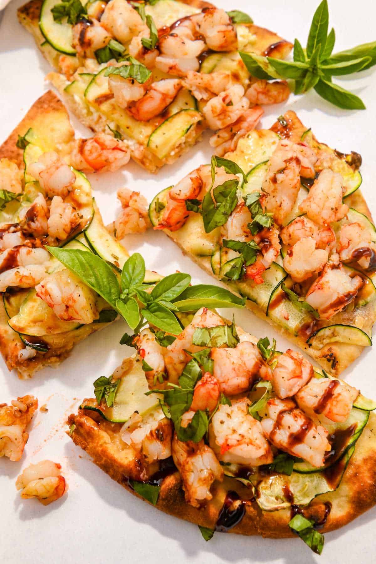 air fryer shrimp pizza cut into slices on a white background.
