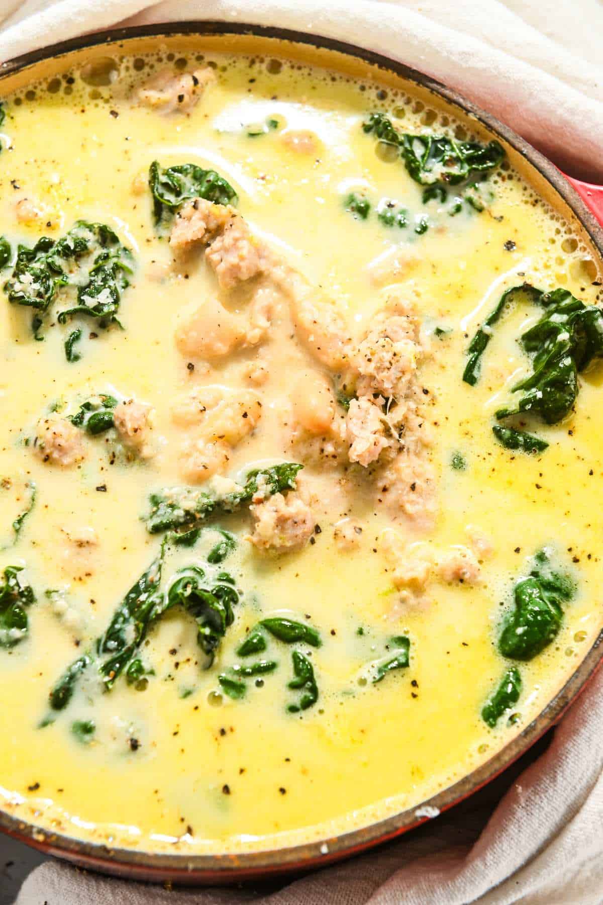 close up of creamy kale soup with sausage and beans.