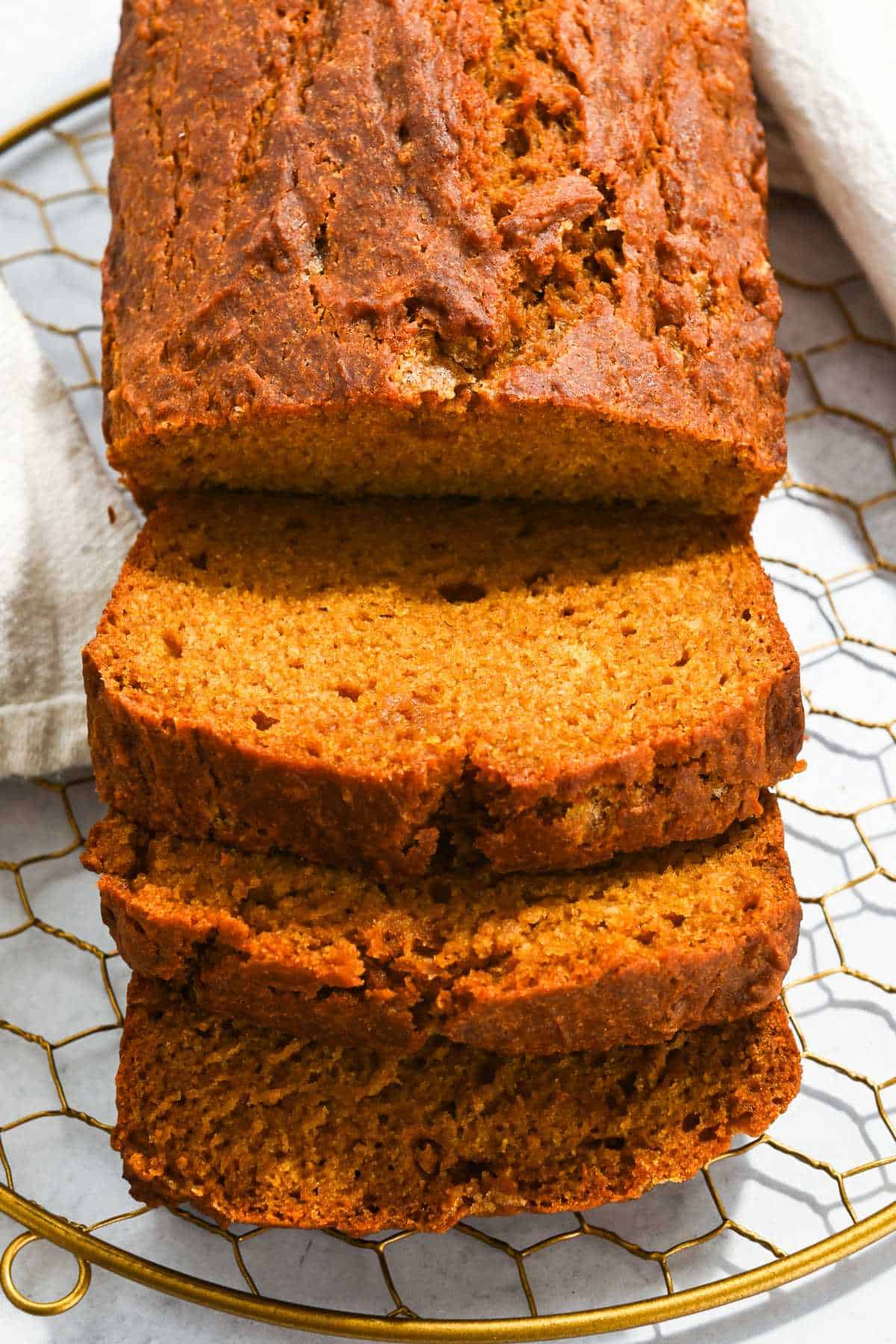 three slices of eggless pumpkin bread on a gold grate.