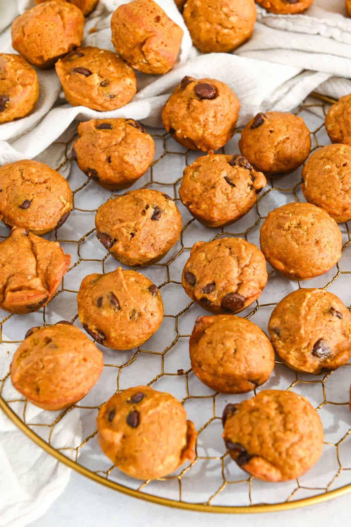mini pumpkin muffins arranged on a gold wire rack.