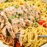 close up of chicken on top of spaghetti aglio e olio.