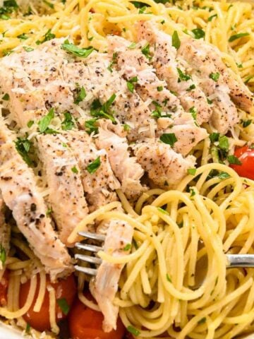 close up of chicken on top of spaghetti aglio e olio.