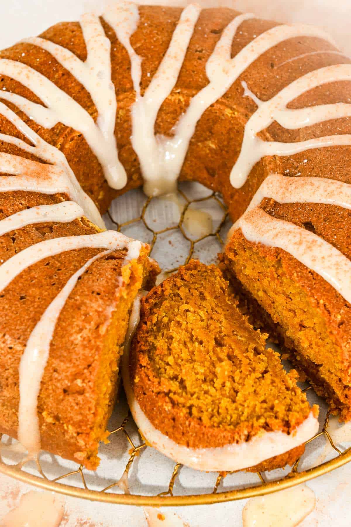 pumpkin bundt cake with cream cheese frosting with a slice cut out.