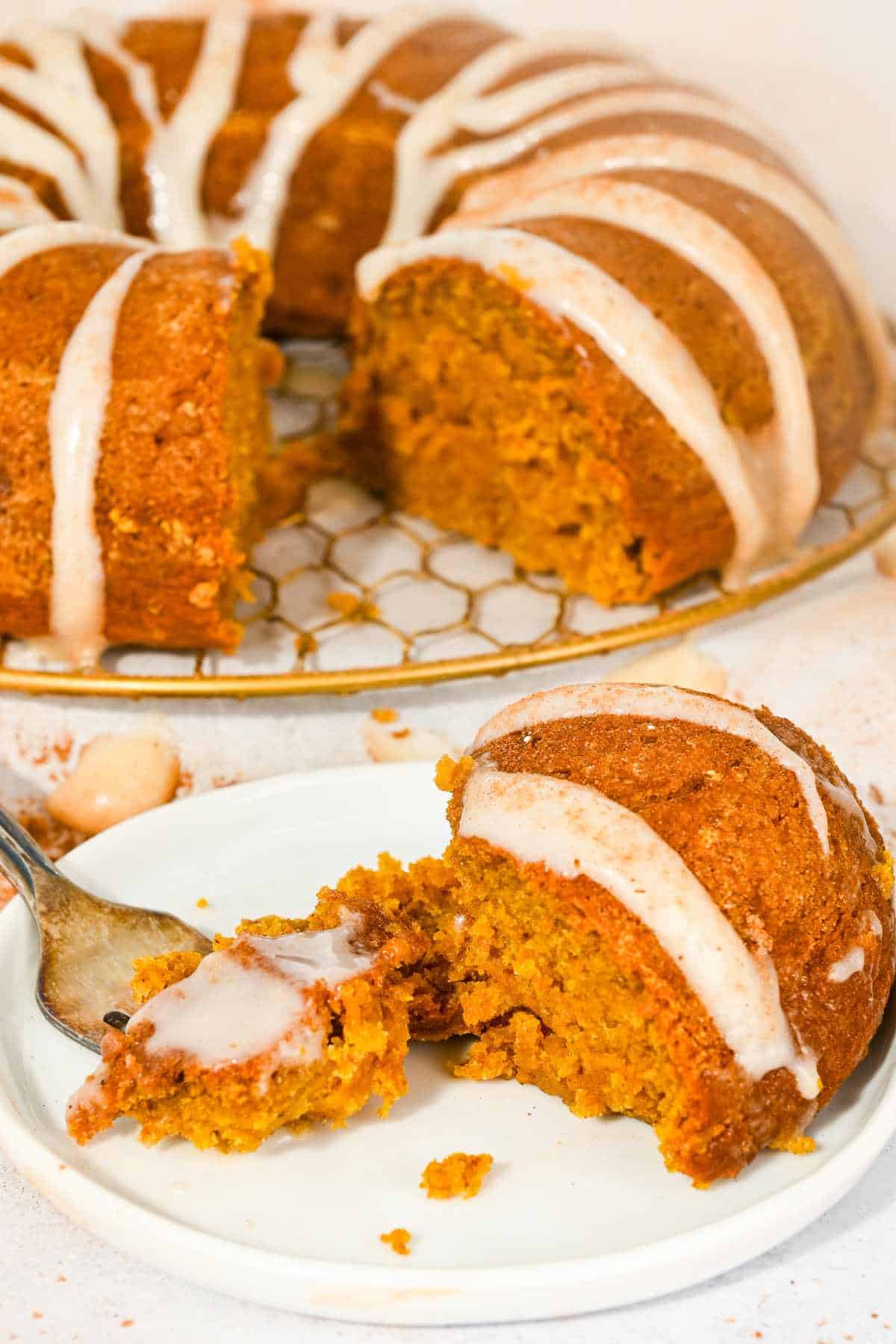 slice of pumpkin applesauce cake on a white plate in front of the bundt cake.