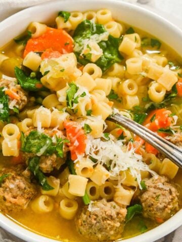 close up of Instant Pot wedding soup in a white bowl with a spoon in it.