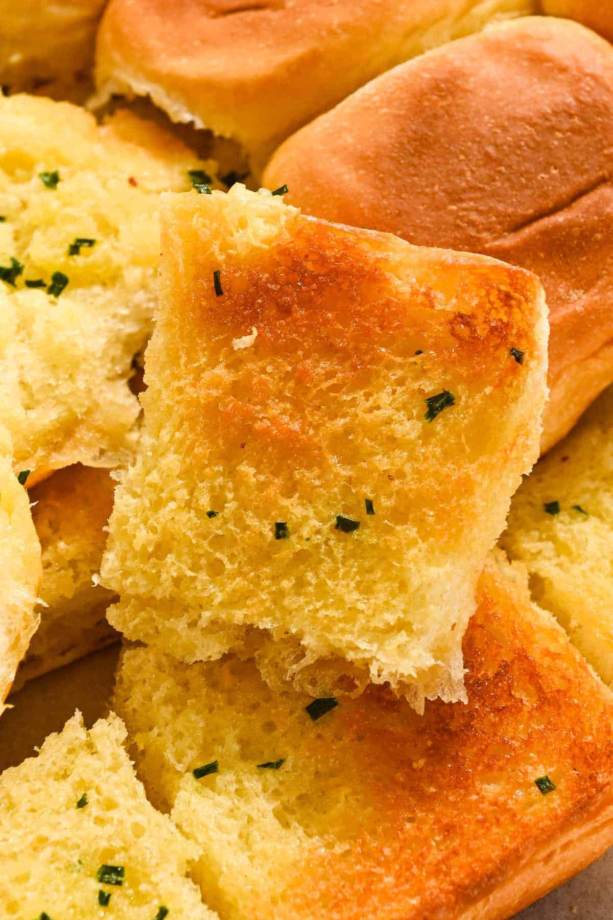 close up of a piece of Hawaiian roll garlic bread.