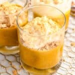 close up of 3 cups of pumpkin pie in a cup topped with whipped cream and graham cracker crumbs.