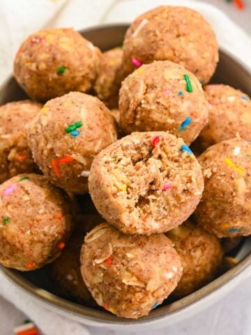 close up of birthday cake protein balls in a white bowl.