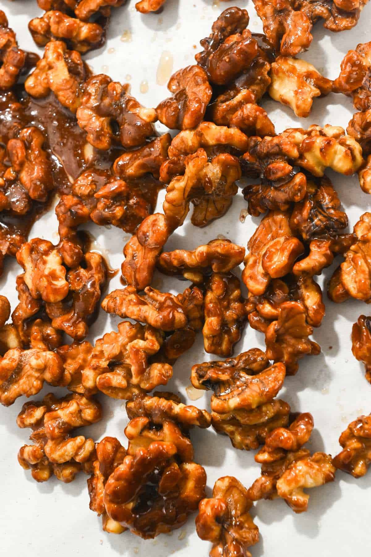 candied Christmas walnuts on a piece of white parchment paper.