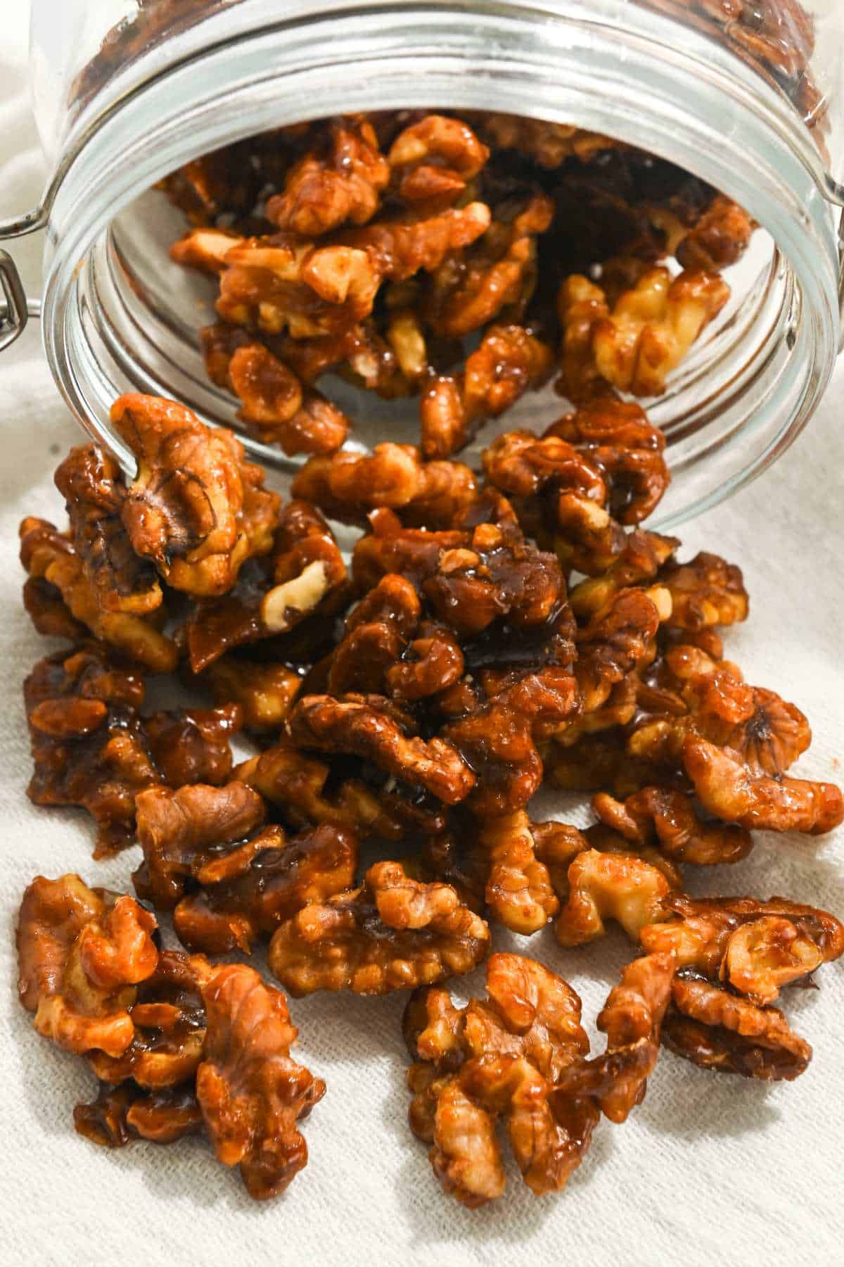 brown sugar candied Christmas walnuts coming out of a glass jar.