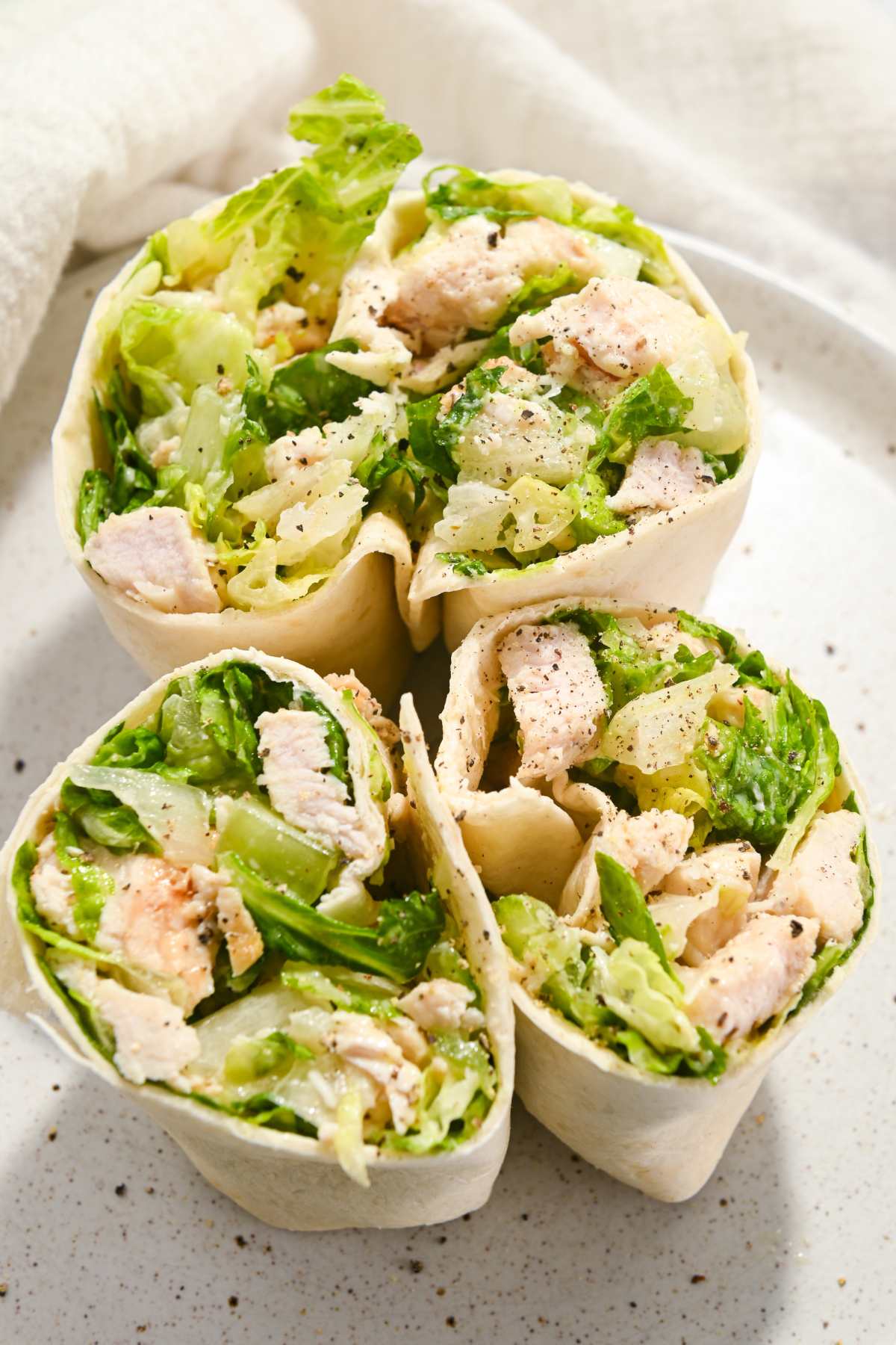 two opened grilled chicken caesar wraps on a white plate.