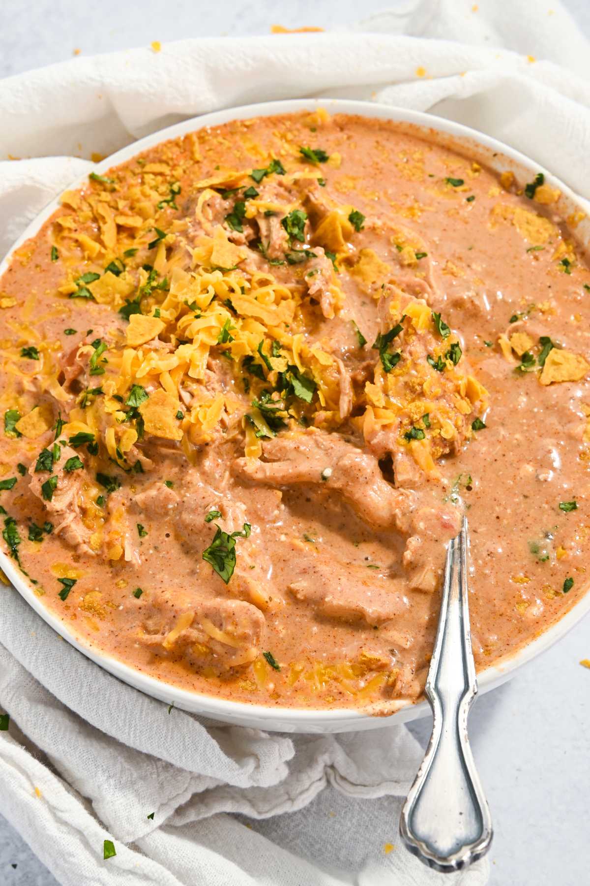 bowl of creamy chicken taco soup in a white bowl with a spoon.