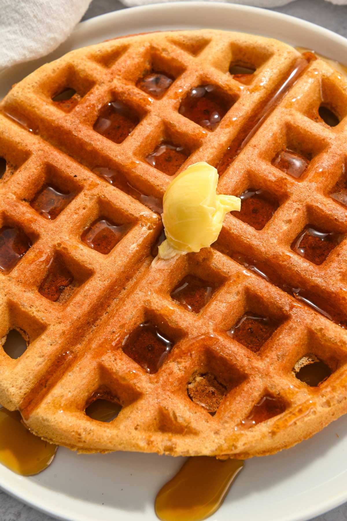 high protein kodiak waffle with butter and syrup on a white plate.