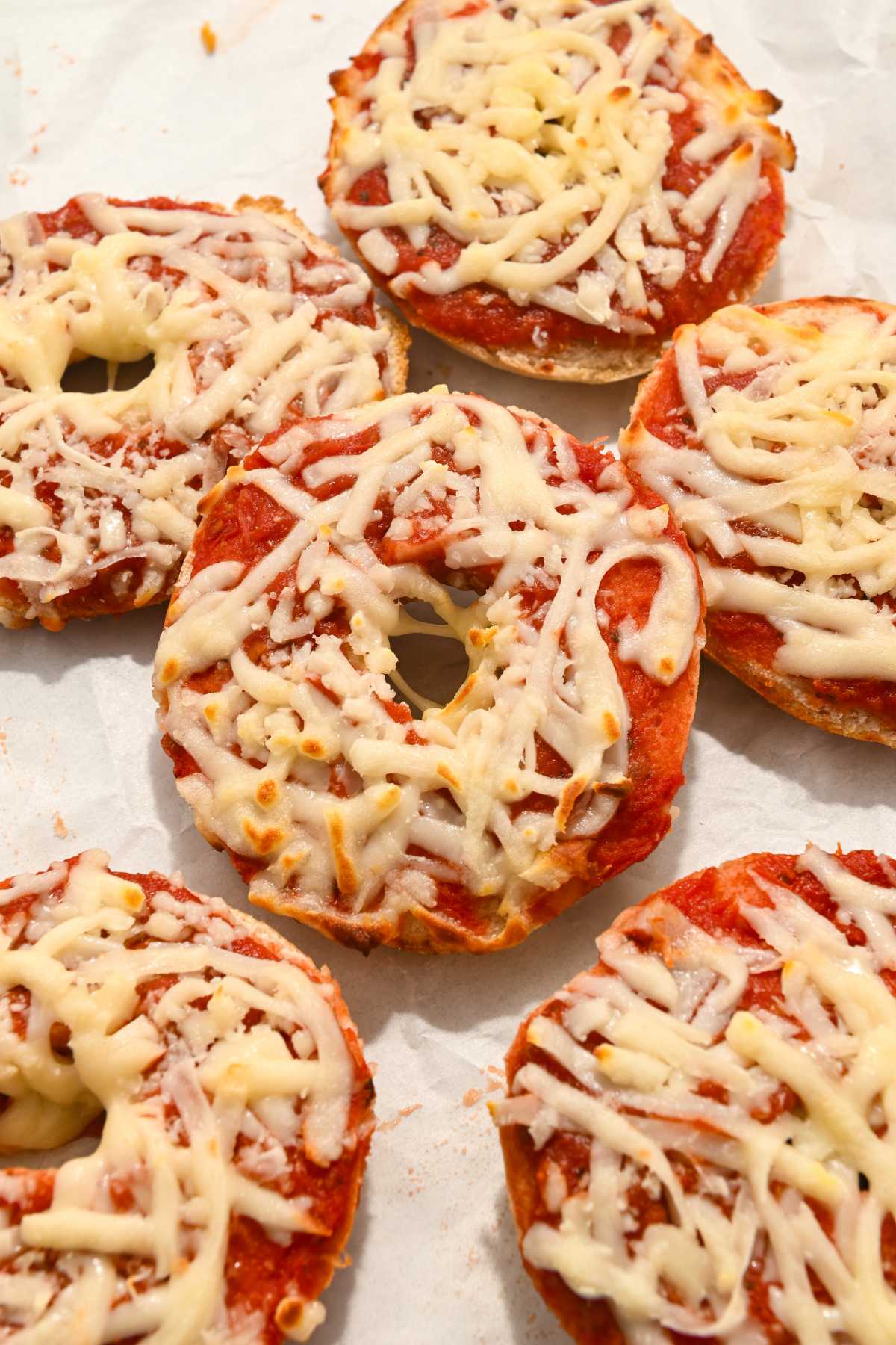 six homemade bagel bites on white parchment paper.