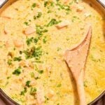 close up of white chicken chili topped with cilantro with a wooden spoon.