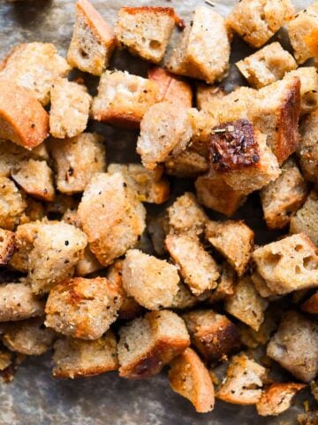 square photo of close up on homemade sourdough croutons on parchment paper.