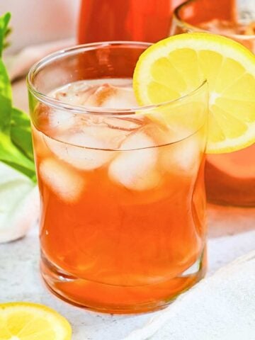 close up of an arnold palmer iced tea lemonade with ice in a glass with a lemon.