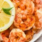 zoomed in photo of Blackstone griddle shrimp topped with seasonings, next to a lemon.