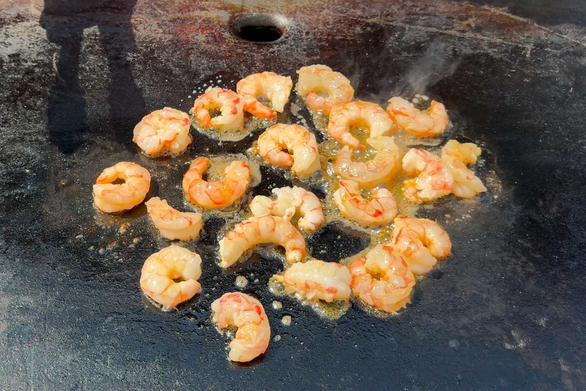 raw shrimp being cooked on the Blackstone griddle.