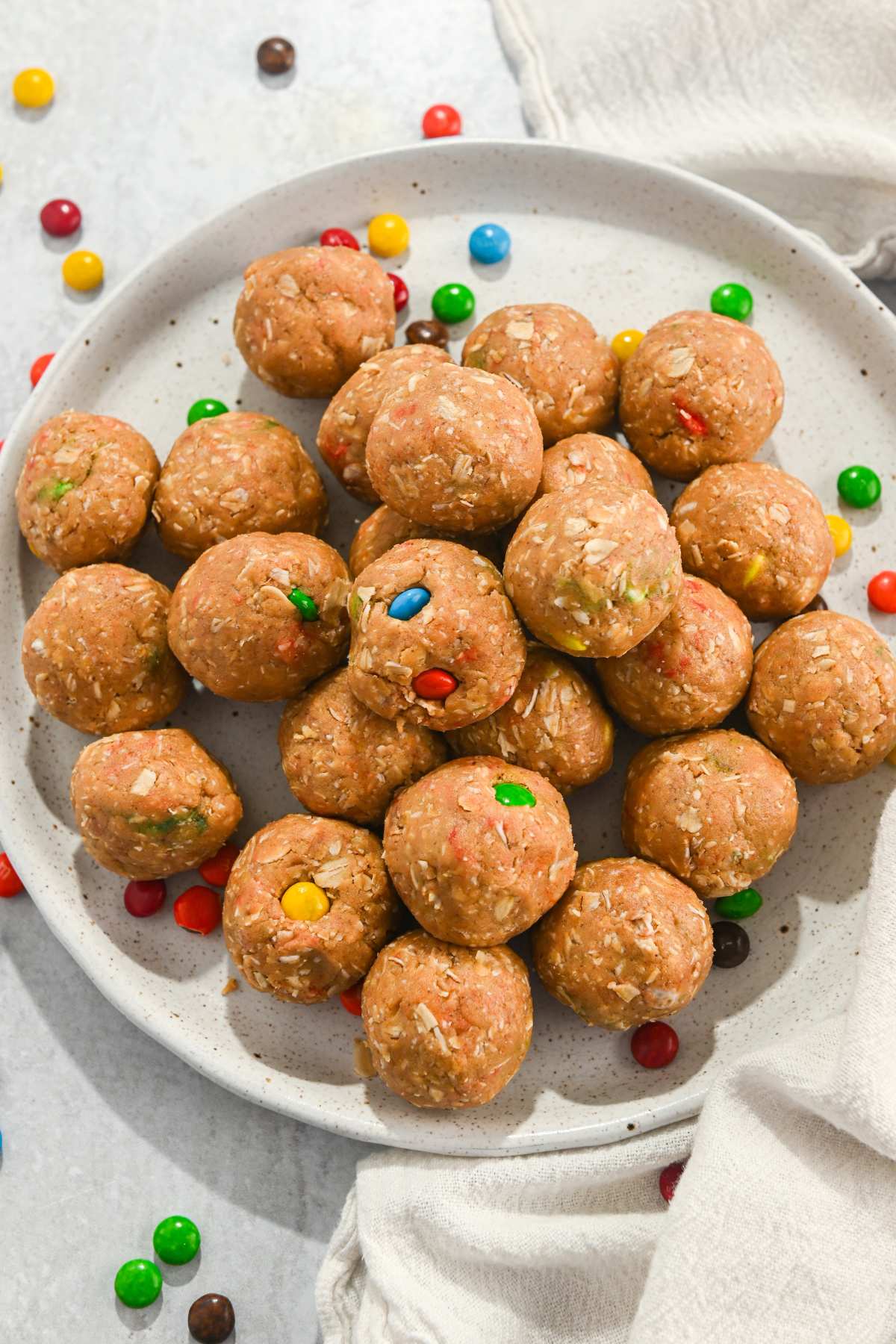 no-bake monster protein balls with m&ms on a white plate.