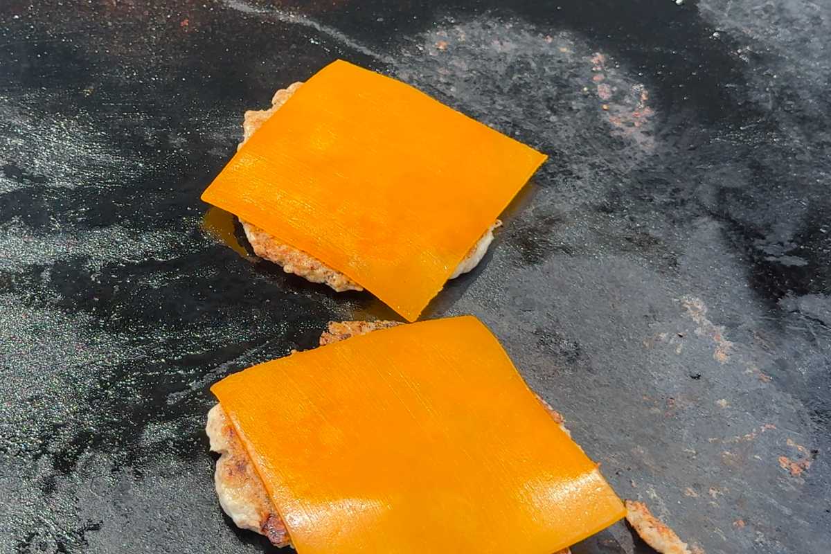 Blackstone turkey smash burgers topped with cheese on a griddle.