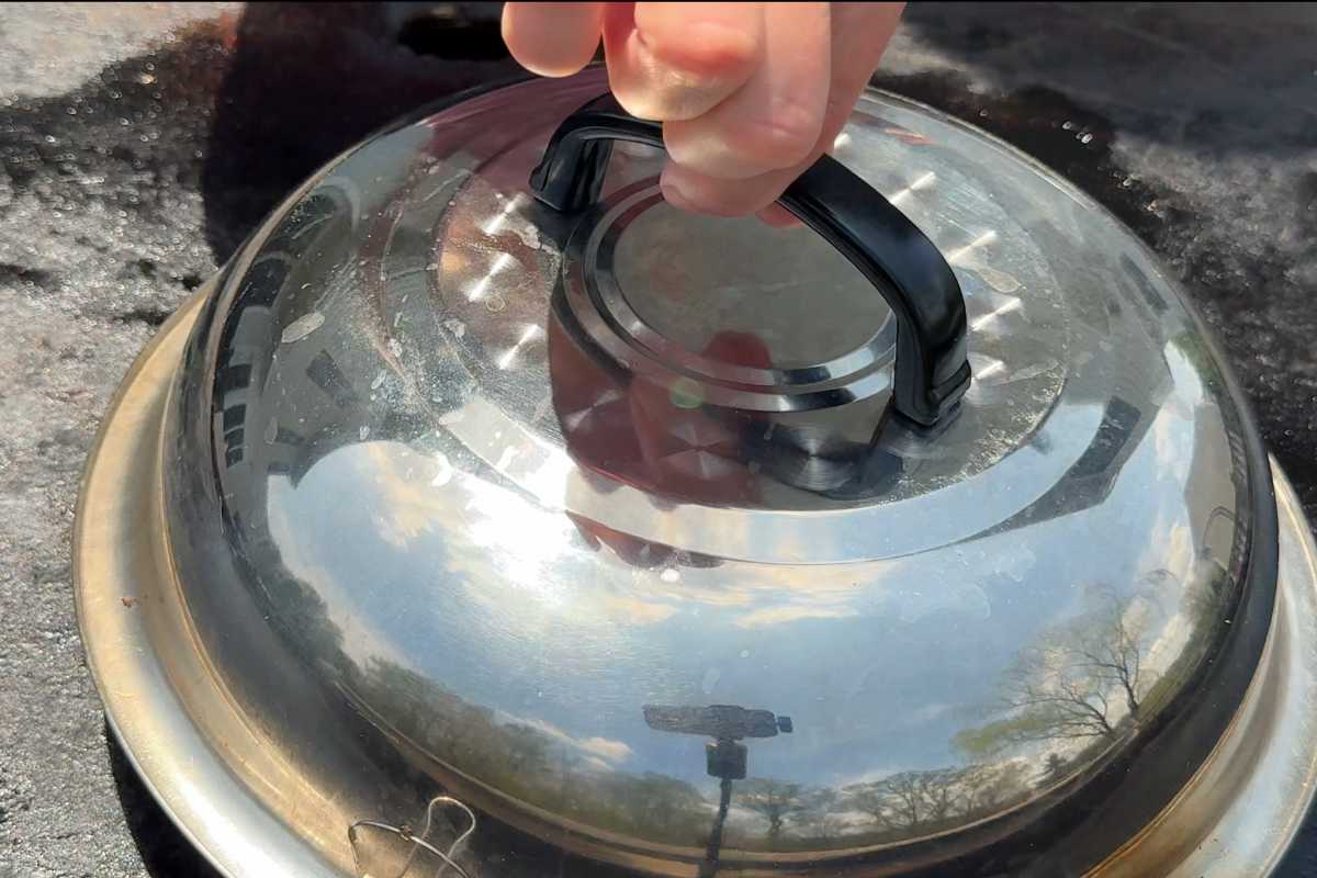 hand holding a burger dome over the top of burgers on a Blackstone grill.